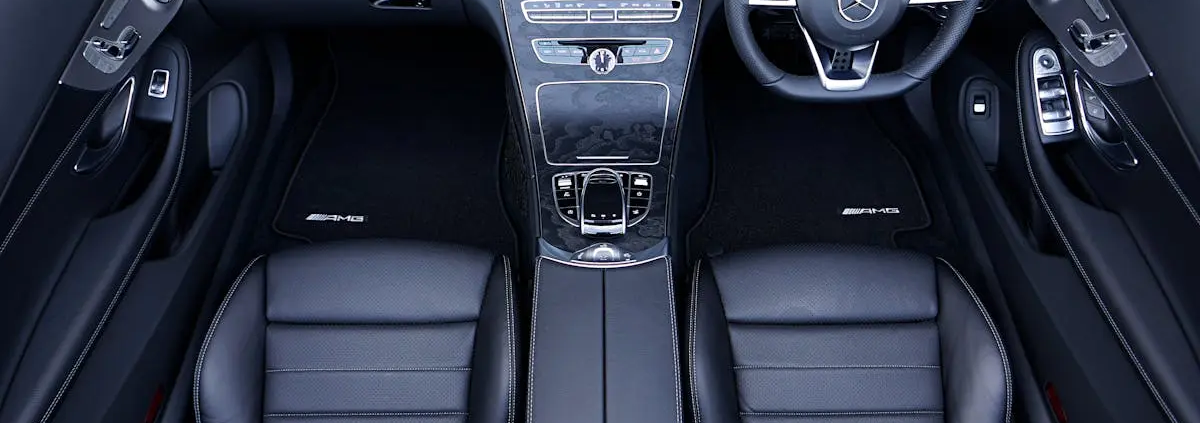 The image showcases the interior of a luxury Mercedes-Benz car, featuring sleek black leather seats, a central console with an elegant design, and detailed stitching, highlighting the premium craftsmanship in the vehicle's restoration.